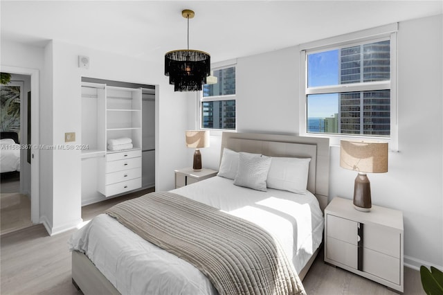 bedroom with a closet, light hardwood / wood-style floors, and a chandelier