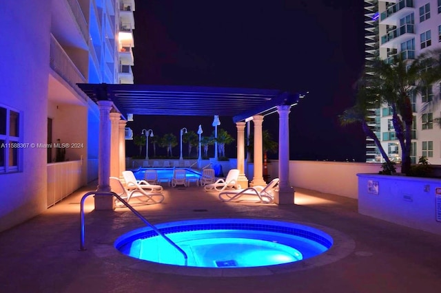 pool at twilight featuring a patio area and a hot tub