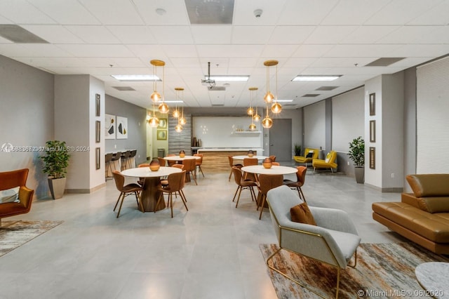 tiled dining area featuring a paneled ceiling and an inviting chandelier