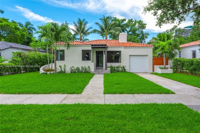 mediterranean / spanish house with a garage and a front lawn