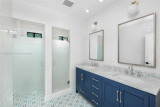 bathroom with dual sinks, tile flooring, vanity with extensive cabinet space, and a shower with shower door