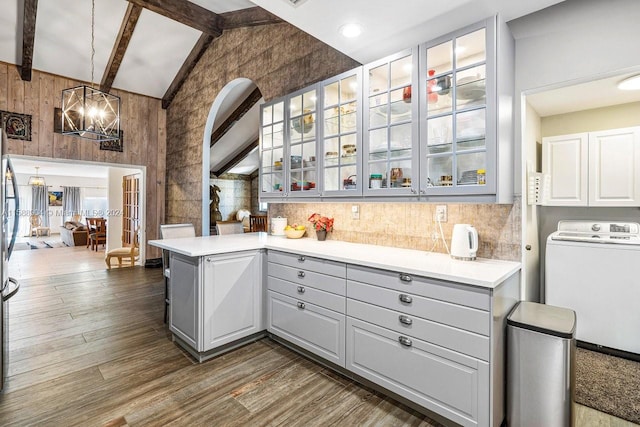 kitchen featuring kitchen peninsula, lofted ceiling with beams, gray cabinets, and dark wood-type flooring