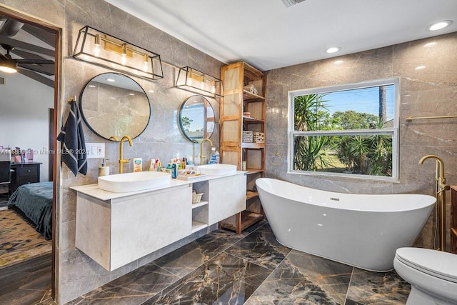 bathroom with tile walls, tile patterned floors, dual vanity, and toilet