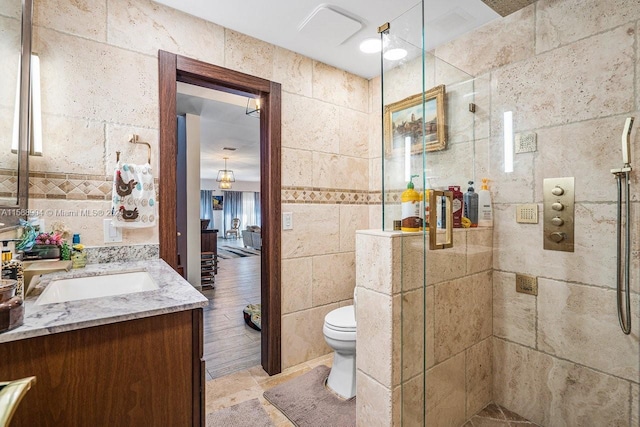 bathroom with toilet, tile walls, an enclosed shower, tile patterned flooring, and vanity