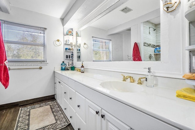 bathroom with double vanity, baseboards, visible vents, wood finished floors, and a sink