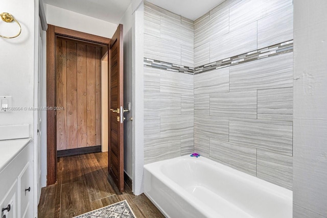 bathroom with hardwood / wood-style floors and tiled shower / bath