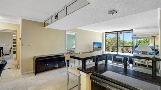 kitchen with light tile patterned floors, a textured ceiling, crown molding, and a breakfast bar area