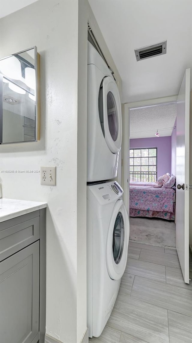 clothes washing area featuring light hardwood / wood-style flooring and stacked washer / drying machine