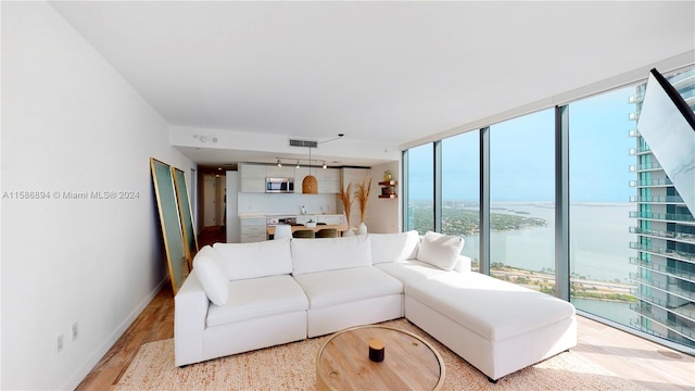 living room with light hardwood / wood-style flooring, floor to ceiling windows, and a water view