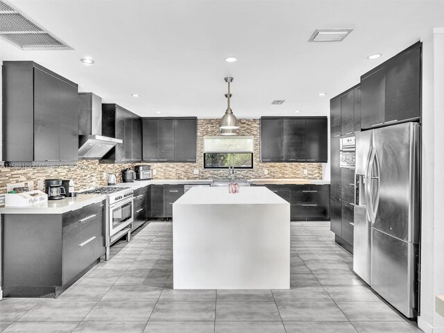 kitchen with hanging light fixtures, tasteful backsplash, appliances with stainless steel finishes, and wall chimney range hood