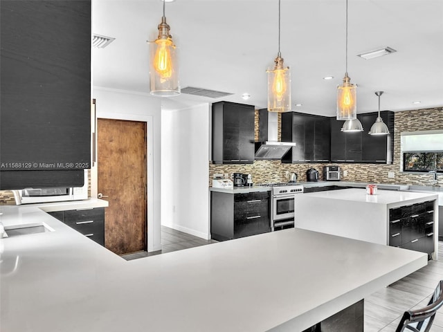 kitchen with a kitchen island, pendant lighting, wall chimney range hood, and stainless steel range