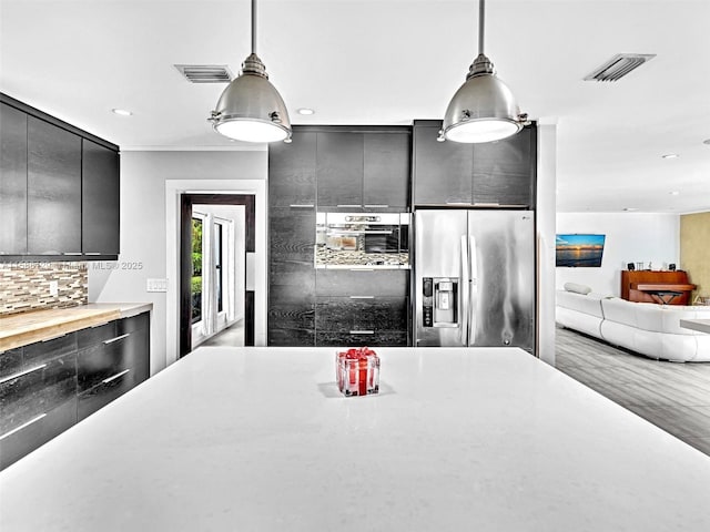 kitchen featuring visible vents, stainless steel fridge with ice dispenser, modern cabinets, decorative light fixtures, and light countertops