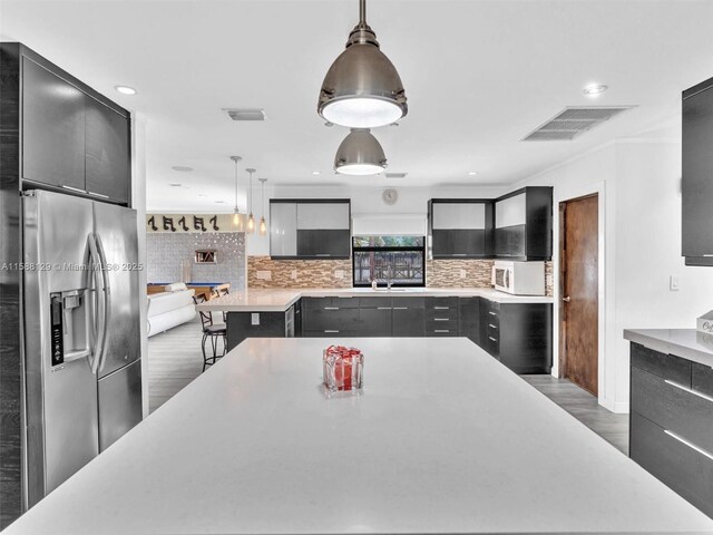 kitchen with sink, hanging light fixtures, kitchen peninsula, beverage cooler, and backsplash