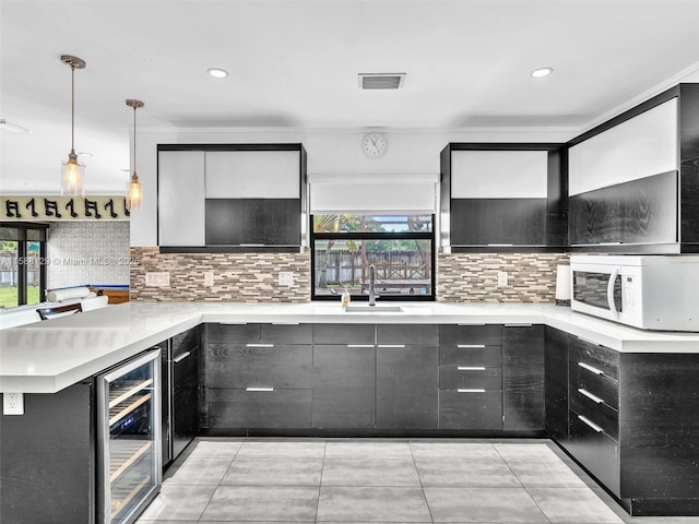 kitchen with white microwave, beverage cooler, pendant lighting, and light countertops