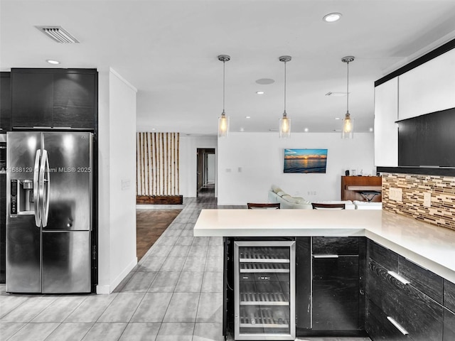 kitchen featuring light countertops, hanging light fixtures, modern cabinets, beverage cooler, and stainless steel fridge with ice dispenser