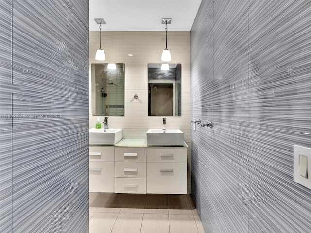 bathroom with a tile shower, double vanity, tile patterned flooring, and a sink