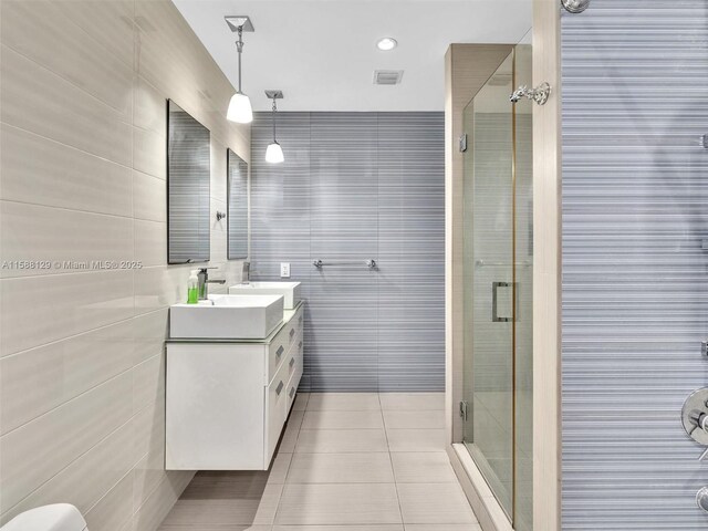 bathroom with tile patterned flooring, vanity, tile walls, and a shower with shower door