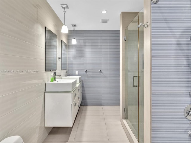 bathroom with tile patterned flooring, visible vents, a sink, and tile walls