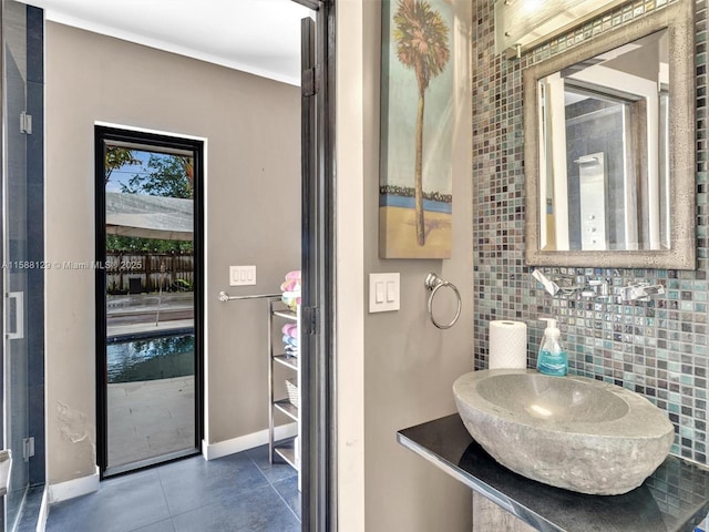 bathroom with a sink, backsplash, tile patterned flooring, and baseboards