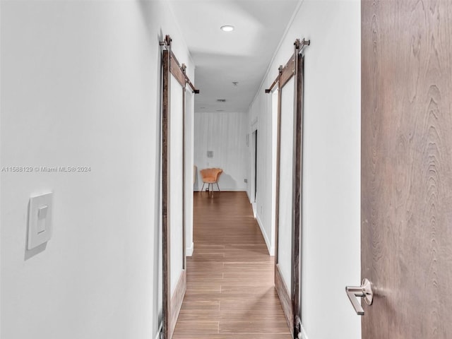 corridor featuring a barn door and light hardwood / wood-style floors