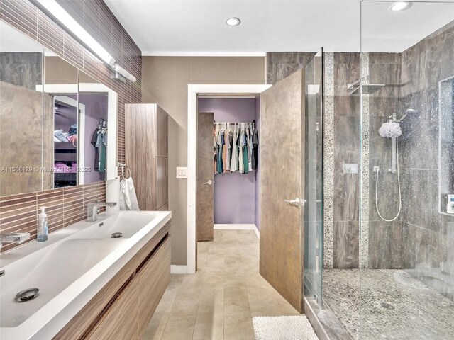 bathroom featuring tile patterned flooring, vanity, backsplash, and walk in shower