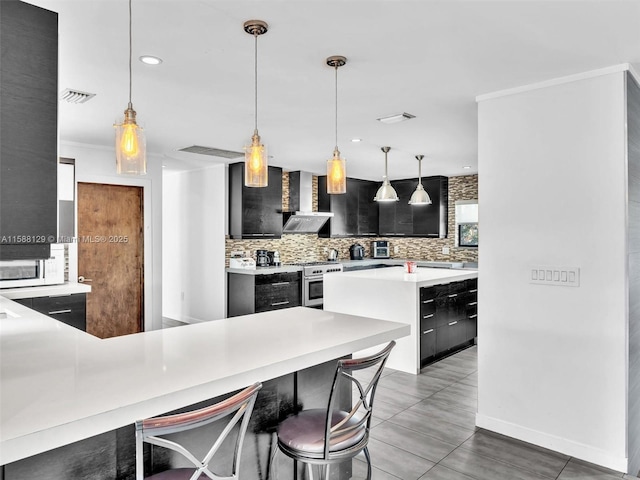 kitchen with pendant lighting, wall chimney range hood, decorative backsplash, and a breakfast bar area