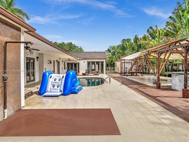 view of pool featuring a ceiling fan, a patio, an outbuilding, fence, and french doors