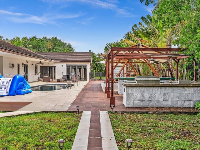 view of patio featuring grilling area, an outdoor bar, and ceiling fan