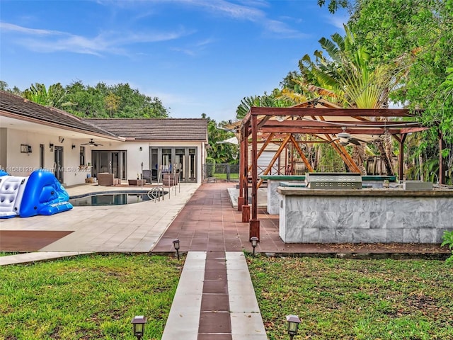 exterior space with fence, a ceiling fan, grilling area, a fenced in pool, and a bar