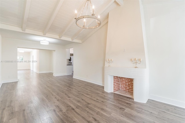 unfurnished living room with a notable chandelier, vaulted ceiling with beams, and hardwood / wood-style floors