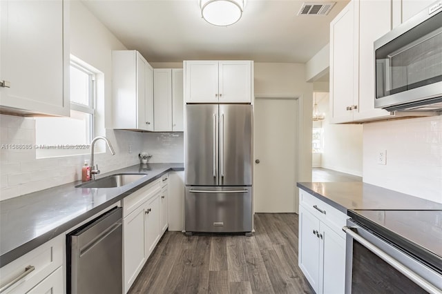 kitchen featuring white cabinetry, dark hardwood / wood-style flooring, stainless steel appliances, backsplash, and sink