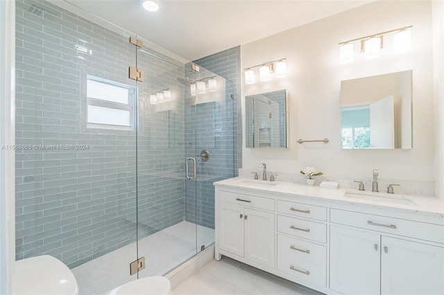 bathroom with vanity with extensive cabinet space, dual sinks, toilet, tile flooring, and a shower with door