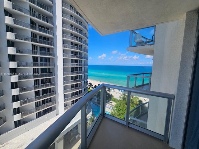 balcony with a water view and a view of the beach