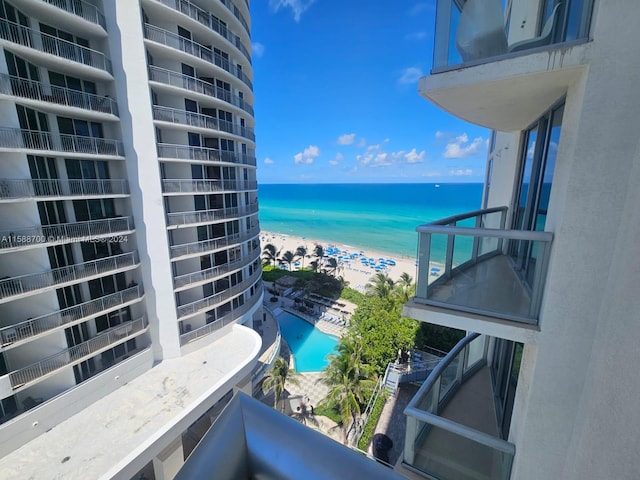 view of pool featuring a patio, a water view, and a beach view