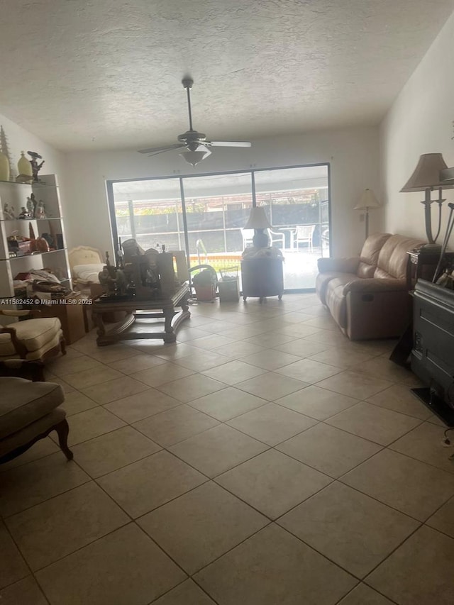 tiled living room featuring ceiling fan, a healthy amount of sunlight, and a textured ceiling