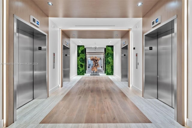 corridor featuring elevator and light hardwood / wood-style floors