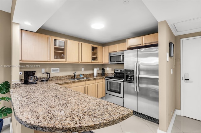 kitchen featuring kitchen peninsula, light brown cabinets, and stainless steel appliances