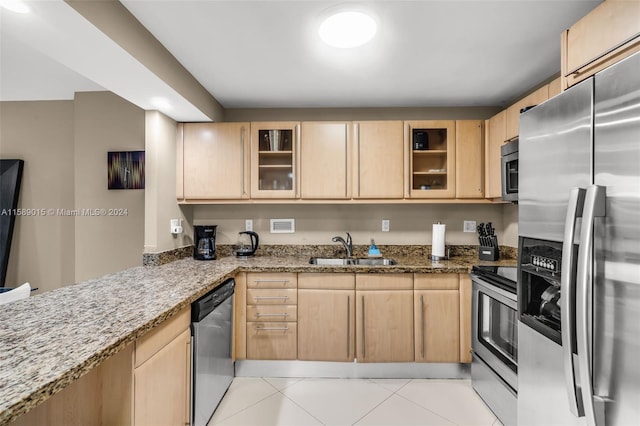 kitchen with light brown cabinetry, light stone counters, sink, and appliances with stainless steel finishes