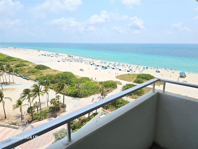 balcony with a water view and a view of the beach