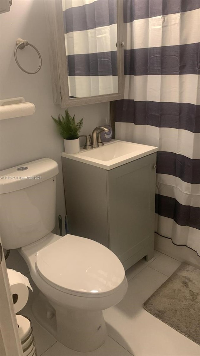 bathroom featuring tile flooring, vanity, and toilet