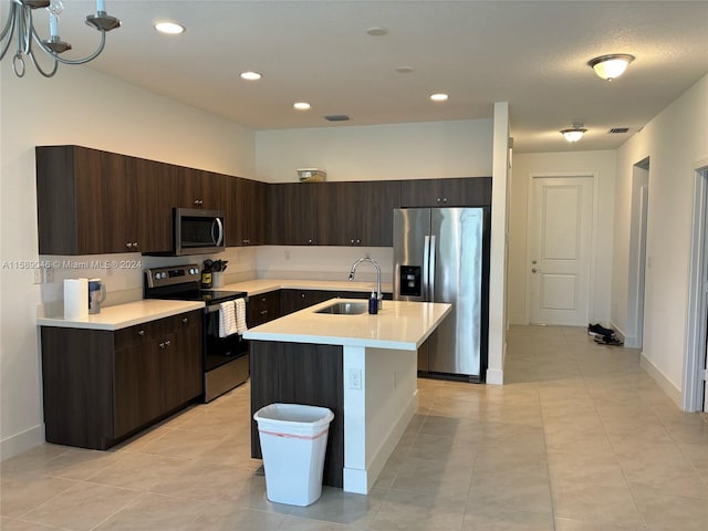 kitchen with dark brown cabinets, an island with sink, light tile floors, sink, and appliances with stainless steel finishes