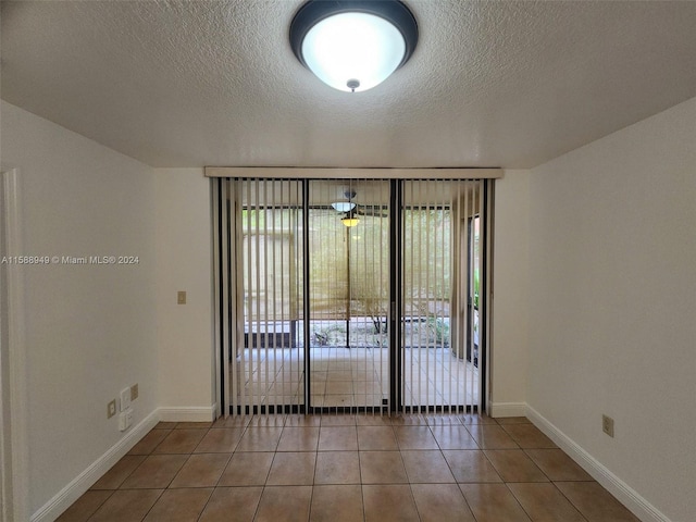 tiled spare room featuring a textured ceiling