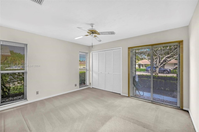 unfurnished bedroom featuring a closet, access to exterior, carpet floors, and ceiling fan