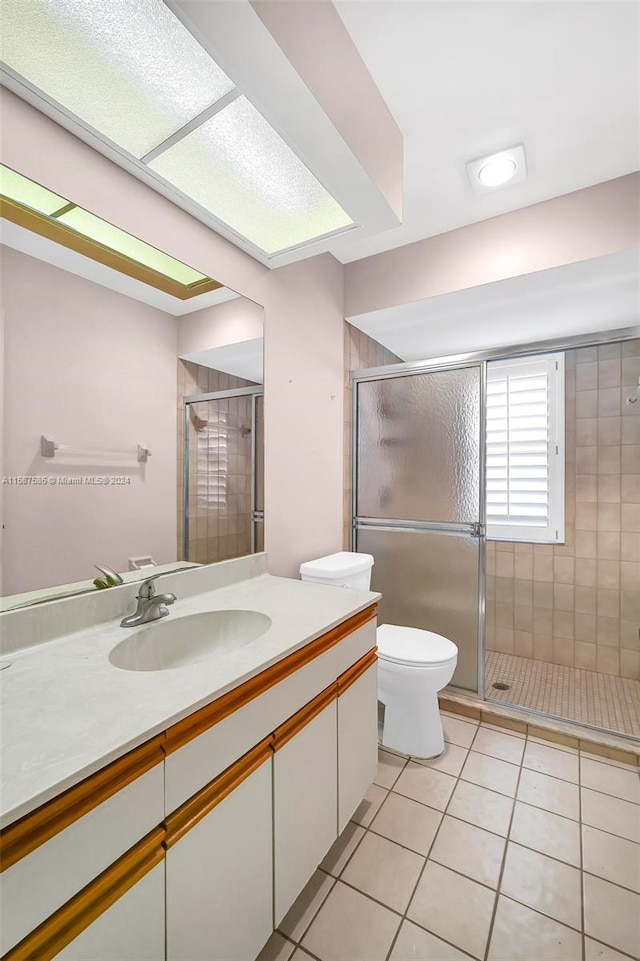 bathroom featuring vanity, toilet, tile patterned flooring, and a shower with door