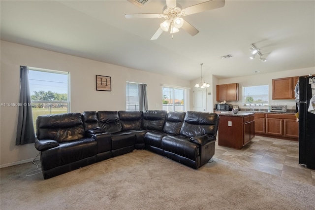 tiled living room with vaulted ceiling, track lighting, sink, and ceiling fan with notable chandelier