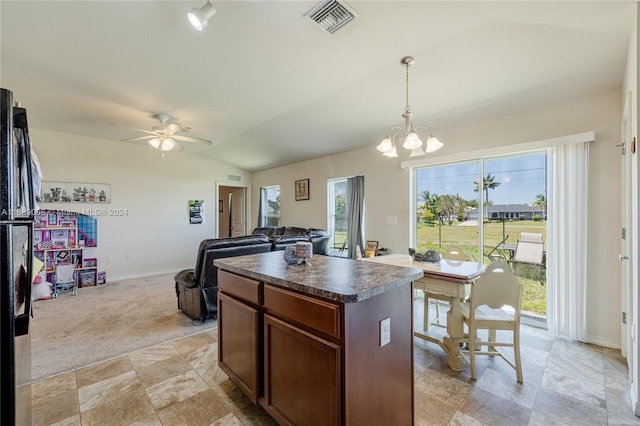 kitchen featuring a healthy amount of sunlight, a kitchen island, light tile floors, and decorative light fixtures