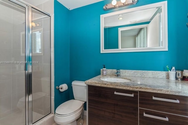 bathroom featuring a shower with door, toilet, and vanity