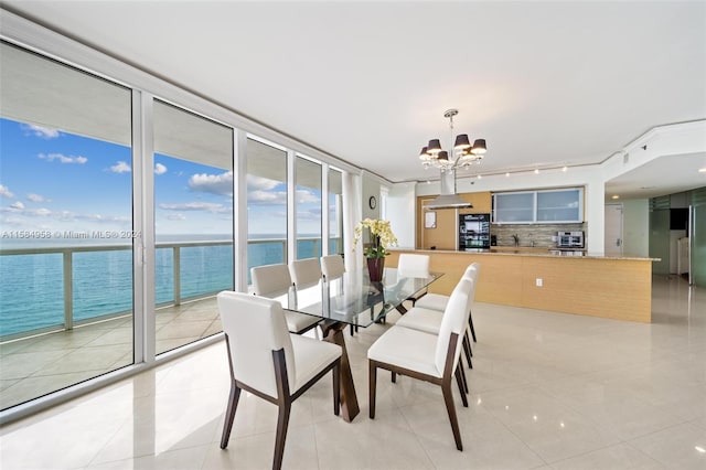 dining area featuring a healthy amount of sunlight, a water view, a chandelier, and light tile floors