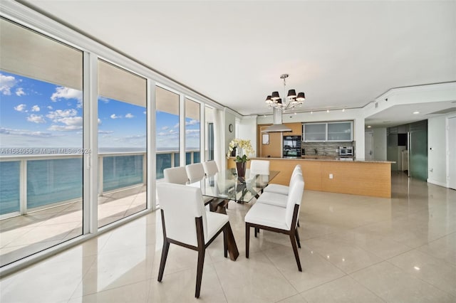 tiled dining area with a chandelier and a water view