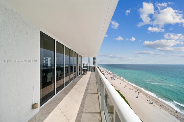 balcony featuring a view of the beach and a water view